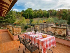 An outdoor patio with a table set for two, surrounded by brick pillars and metal chairs, overlooking a scenic hillside. - Farmhouse Umbria-Tuscany with Pool (Città Della Pieve)