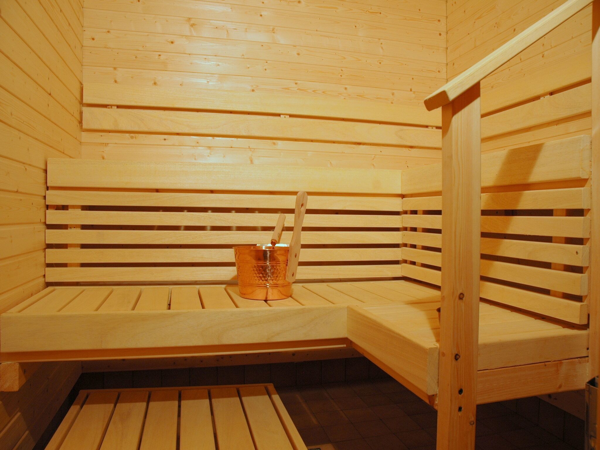 A sauna with wooden benches and a small table with a container.