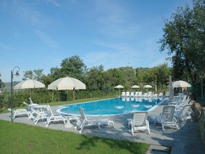 A swimming pool with lounge chairs and umbrellas, surrounded by greenery. - Farmhouse Umbria-Tuscany with Pool (Città Della Pieve)