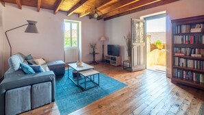 A cozy living room with a wooden ceiling, a sofa, a coffee table, a TV, a bookshelf, and a door leading outside. - Tranquil Escape in Loubejac (Loubejac)