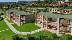Un hotel moderno con diversi piani, zone con posti a sedere all'aperto e un prato curato.