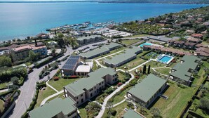 Vista aerea di una zona residenziale con un porto turistico, prati verdi e una piscina.