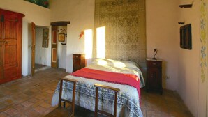 Een traditionele slaapkamer met een bed, houten meubels en een betegelde vloer.