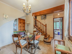 A dining area with wooden furniture, a chandelier, and a staircase.