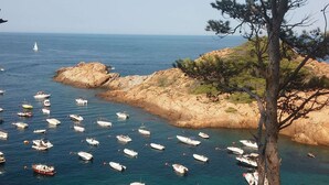A coastal area with numerous boats anchored near rocky terrain and sparse vegetation. - Belvilla by OYO Casa Rey (Begur)