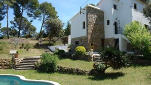 A two-story house with a stone facade, a swimming pool, and a garden with steps leading up to the house. - Belvilla by OYO Casa Rey (Begur)