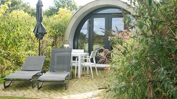A patio with two lounge chairs, a table, and an umbrella.