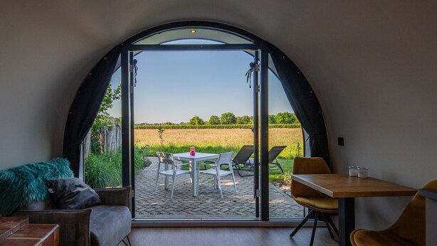 Una habitació amb un gran finestral d'arc, una taula amb cadires i vista a un camp obert.
