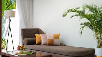 A modern living room with a sofa, a side table, a lamp, and a potted plant.