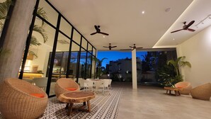 An indoor-outdoor lounge area with wicker furniture, ceiling fans, and a view of the outside. - WAKA VILLA Private Resort & Spa 16 + Adults Only (Siem Reap)