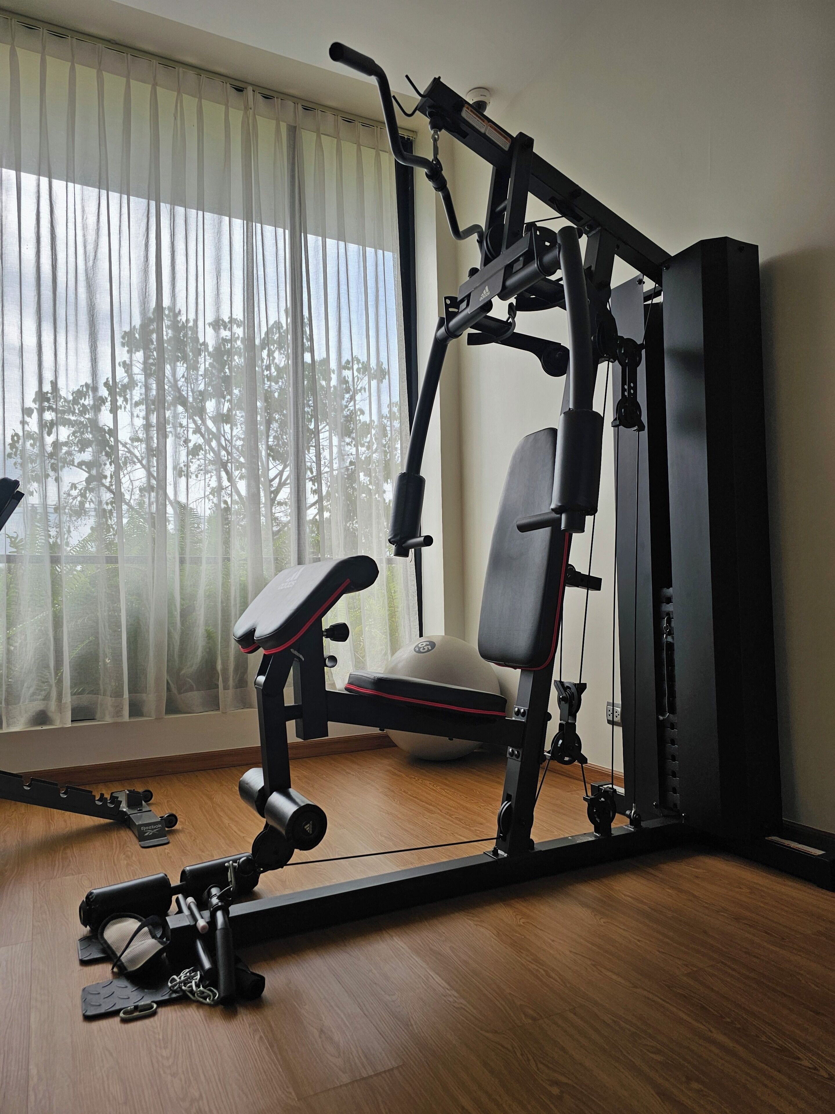 A home gym with a bench press, a cable machine, and a medicine ball.