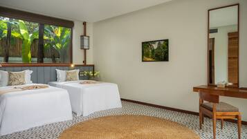 A room with two beds, a large window with a view of greenery, a wooden desk, and a mirror.