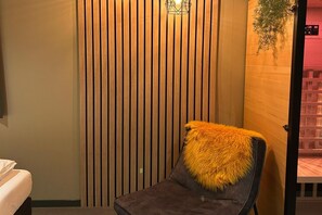 Una stanza con una parete in listelli di legno verticale, una poltrona con una coperta in pelliccia e una pianta sospesa.