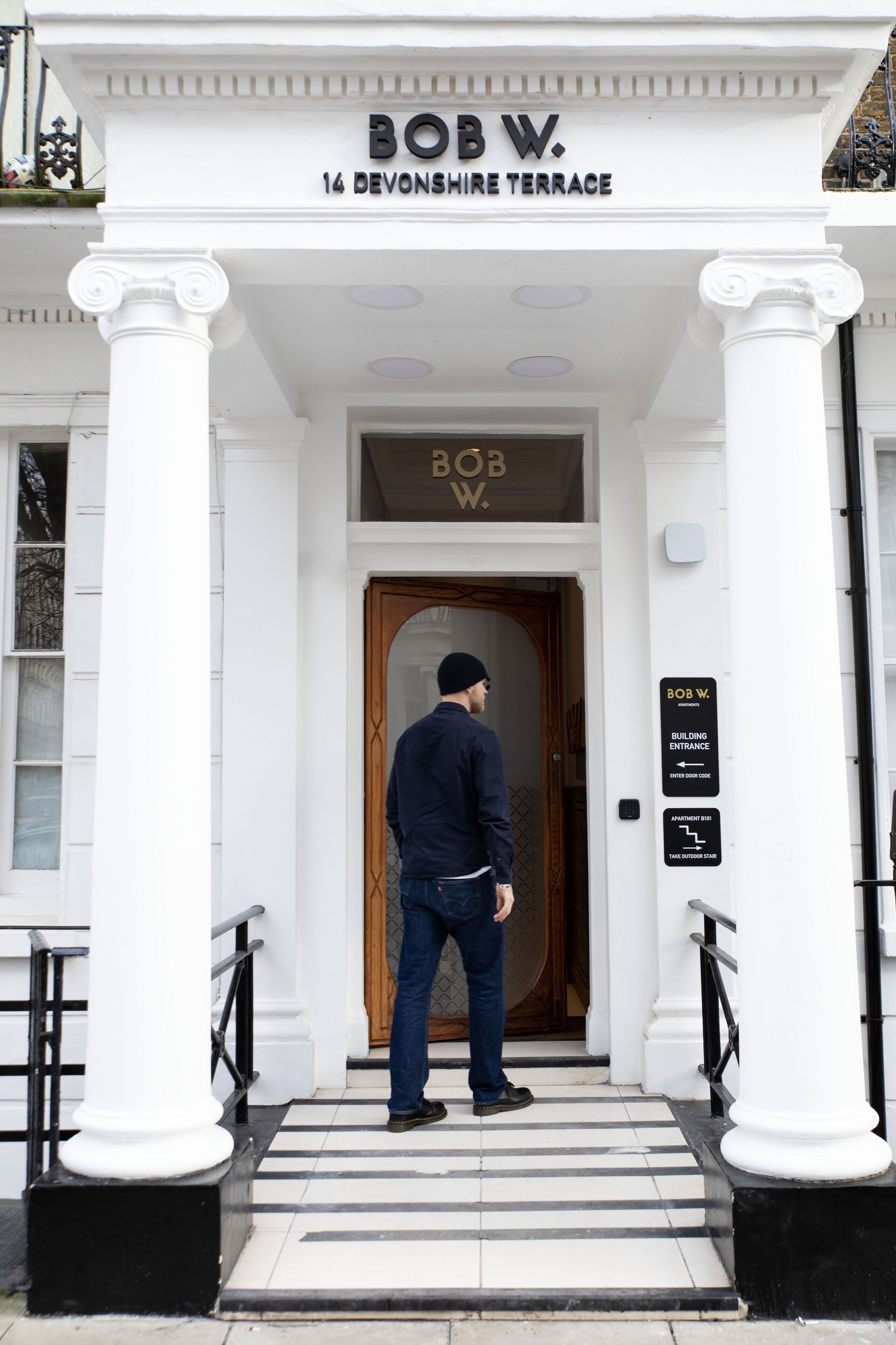 De ingang van Bob W. 14 Devonshire Terrace, met een man die bij de deur staat.