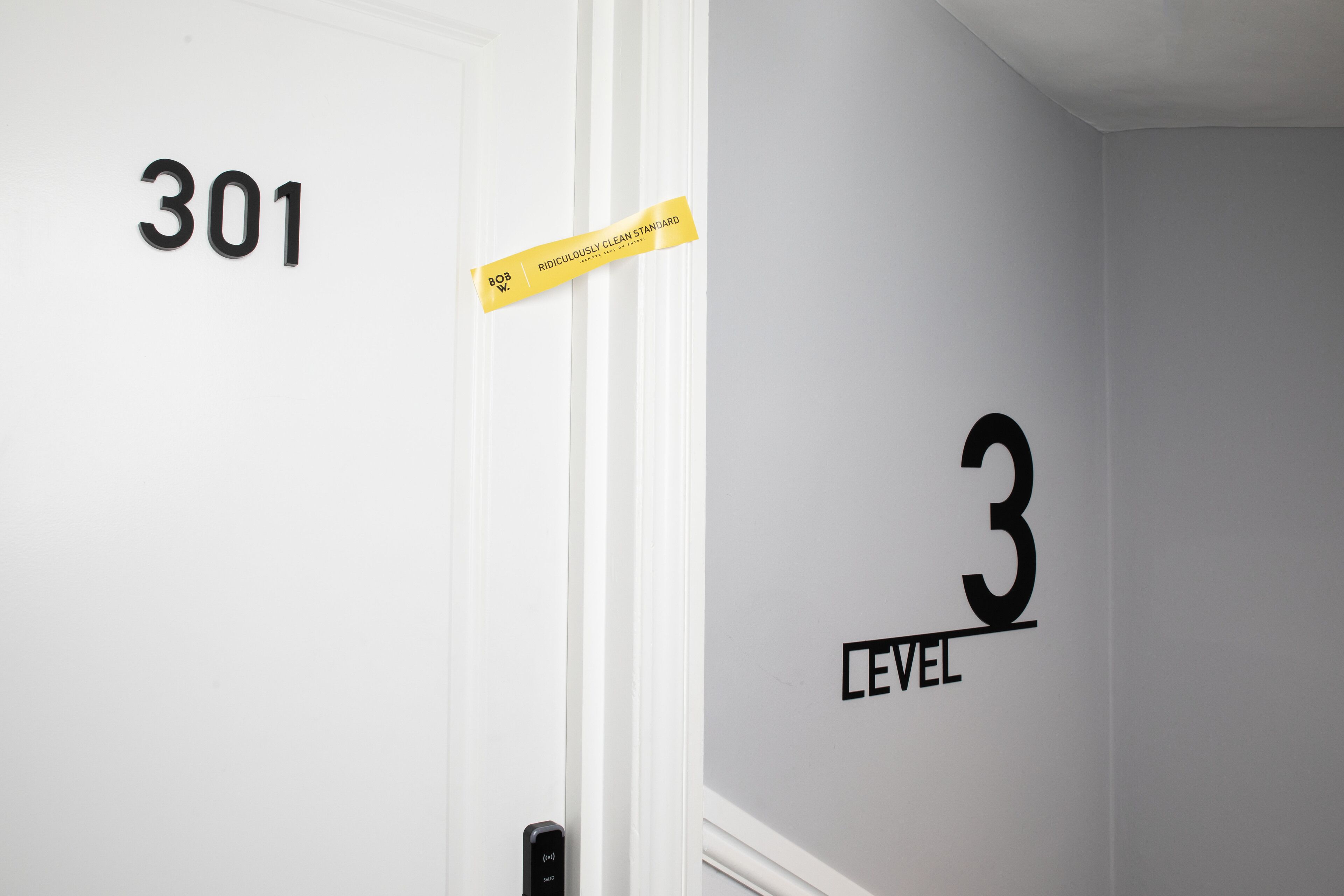 Una puerta con el número 301 y cinta amarilla con texto.
