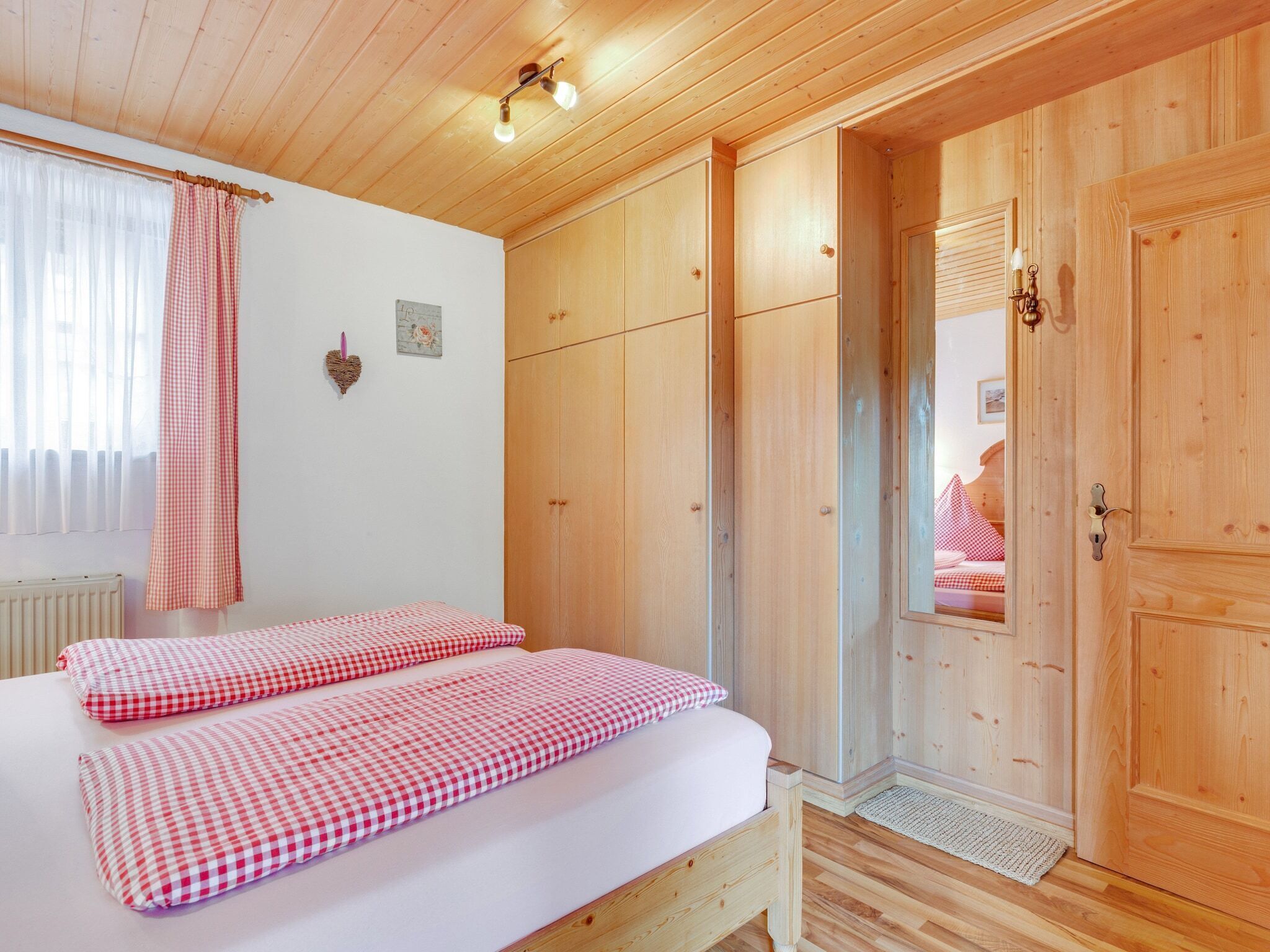 Un dormitorio con una cama de madera, un armario y un espejo.