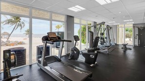 A gym with a treadmill, elliptical, and weight machines, large windows with a beach view, and a clean, modern design. - Reel Paradise at Sea Gulls (Tavernier)