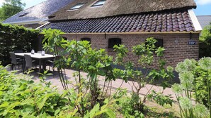 A brick building with a tiled roof and a small window. There is a table and chairs outside. - Apartment in Netherlands near Nature Trails (Dalerveen)