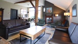 A spacious living room with a high ceiling, a fireplace, and a dining area. - Apartment in Netherlands near Nature Trails (Dalerveen)