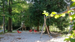 A playground with swings and a slide, surrounded by trees. - Cozy apartment in a 16th-century castle (Aywaille)