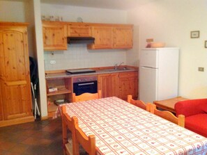 A compact kitchen with wooden cabinets, a built-in oven, a sink, and a white refrigerator.