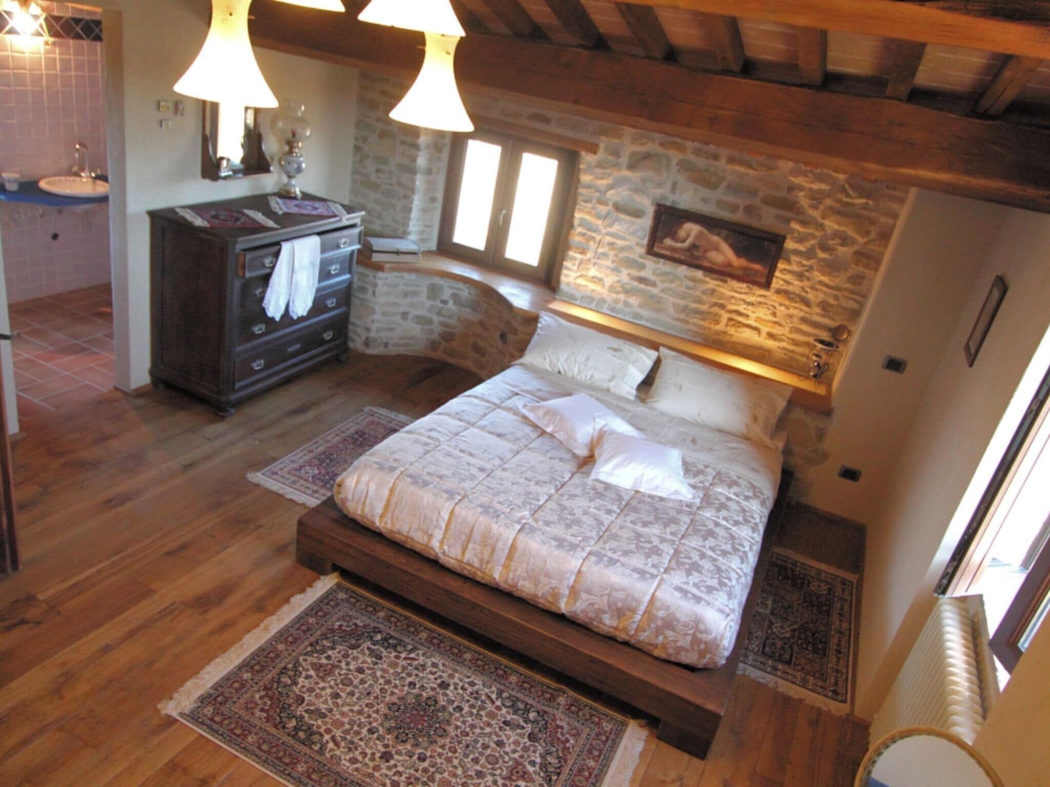 Een slaapkamer met een houten bed, een stenen muur en een rustiek plafond.
