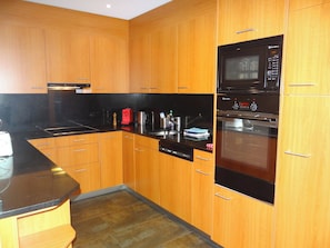 A kitchen with wooden cabinets, a black countertop, a microwave, and an oven.