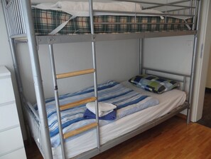 A bunk bed with a wooden ladder, a pillow, and a folded towel.