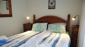 A bed with a striped blanket, two bedside lamps, and a poster on the wall.