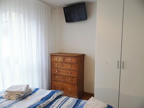 A bedroom with a bed, a wooden dresser, a wardrobe, and a television mounted on the wall. - Bellevue-Park B 145 Appartement/Fewo 6-Bettwohnung by Interhome (Engelberg)