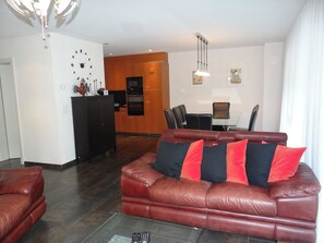 A living room with a leather sofa, a dining area with a table and chairs, and a kitchen with appliances. - Bellevue-Park B 145 Appartement/Fewo 6-Bettwohnung by Interhome (Engelberg)