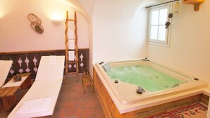 Ett spa-rum med en trästege, ett stort badkar och två massagebänkar.