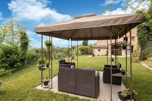 A covered outdoor seating area with wicker furniture and potted plants. - Country House with Saltwater Pool (Acqualagna)