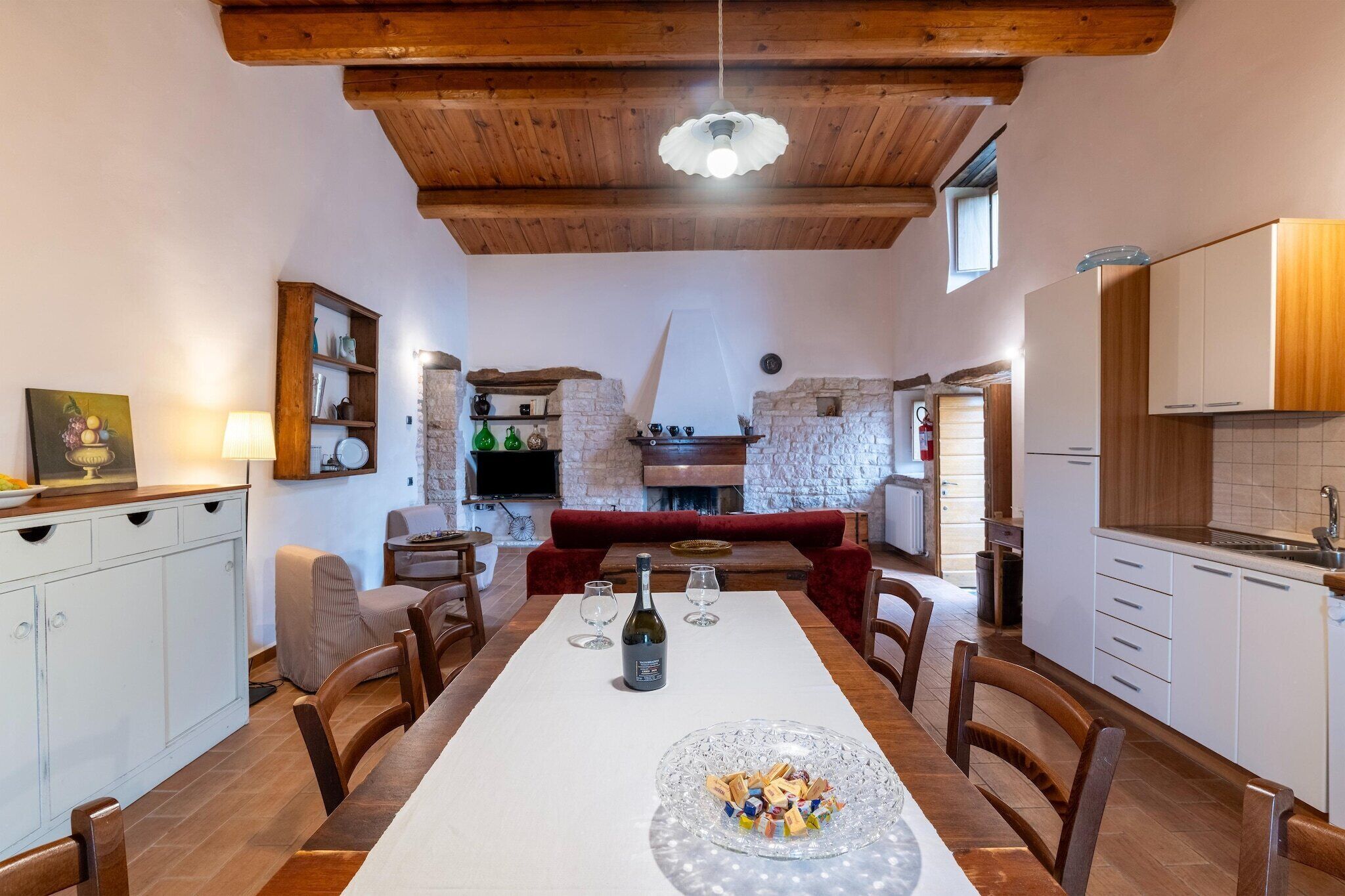 Un coin repas avec une longue table, des chaises, une bouteille de vin et une assiette décorative.