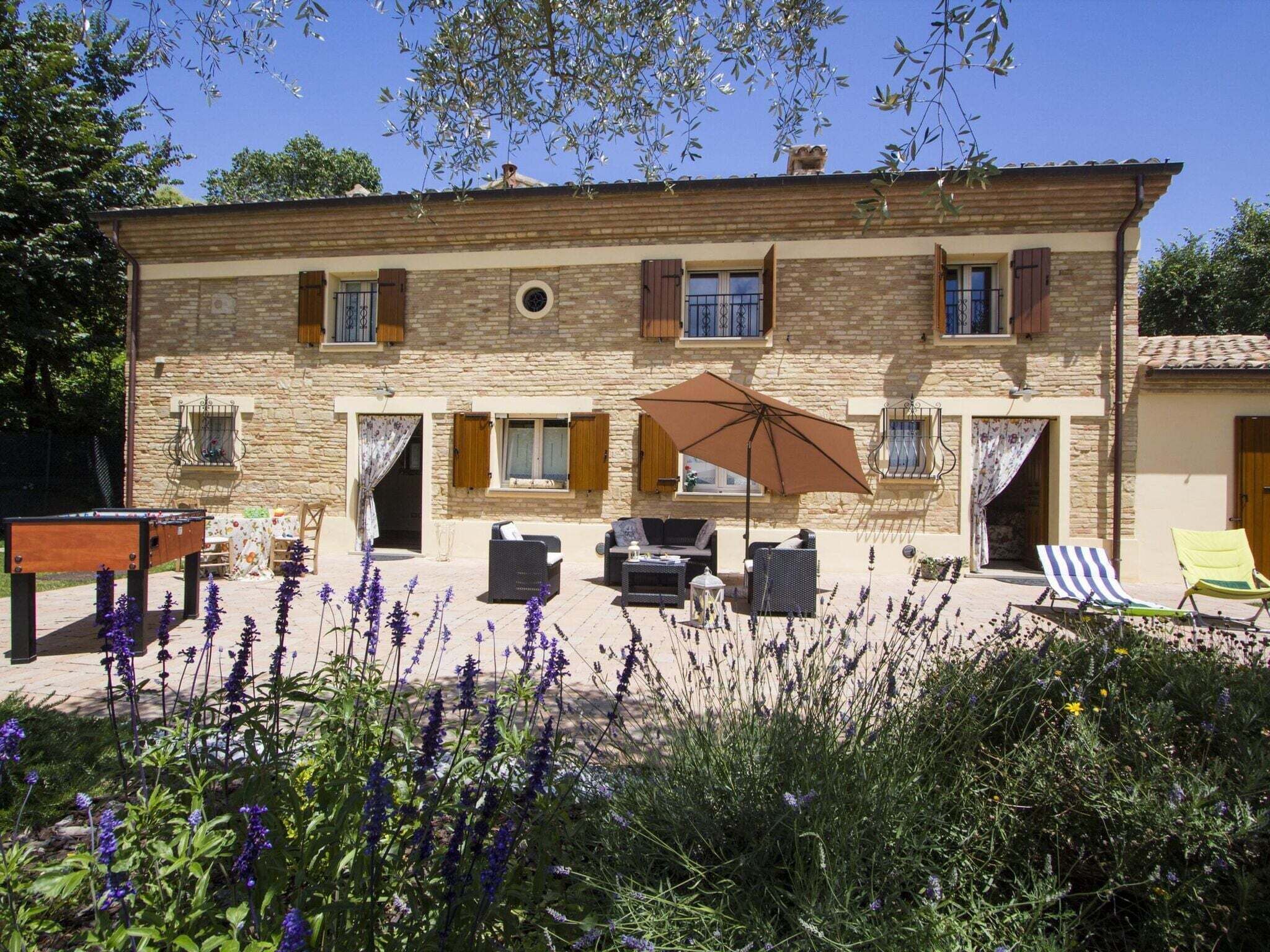 A two-story stone building with a patio area featuring outdoor furniture and a pool table. - Holiday Home in Fano near Adriatic Sea (Fano)