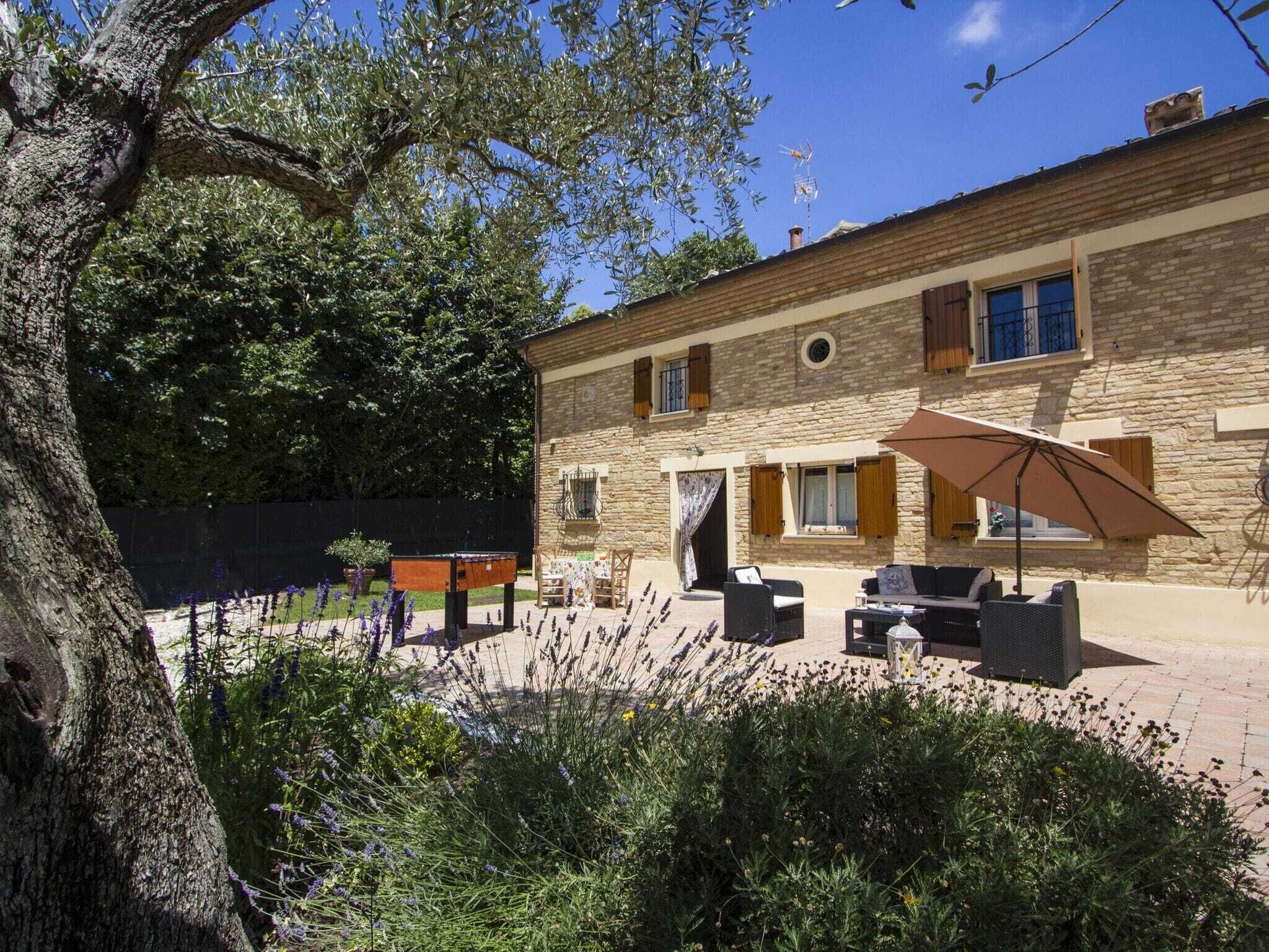 Un bâtiment en pierre doté d’un patio, de mobilier d’extérieur et d’un grand parasol.