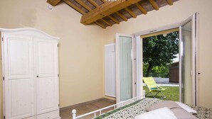 A bedroom with a bed, a wardrobe, and a sliding glass door leading to an outdoor area with a lawn and a chair. - Holiday Home in Fano near Adriatic Sea (Fano)