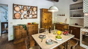 Una cocina rústica con armarios de madera, un colgador para ollas y una mesa de comedor con platos y cubiertos.