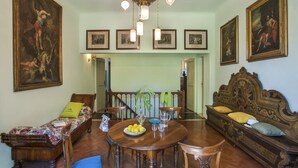 Un comedor con mesa y sillas de madera, rodeado de sofás y una escalera.
