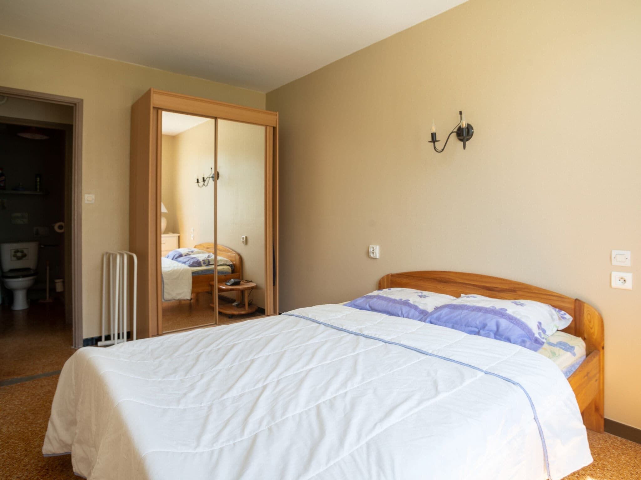 Une chambre à coucher avec un lit, une armoire et un miroir.