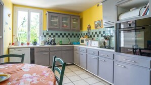 A kitchen with grey cabinets, a Bosch refrigerator, and a window with potted plants on the counter. - Pretty holiday home with garden and hot tub (Bédoin)