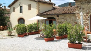 A courtyard with potted plants, outdoor furniture, and a building with a tiled roof. - Idyllic Tuscan Hideaway with Pool and spa (Montorsoli)
