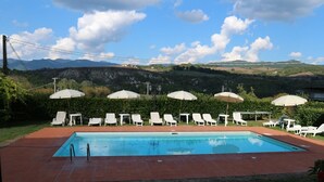 A rectangular swimming pool with white lounge chairs and umbrellas arranged around it. - Villa Life in Vicchio; the Tuskan way (Vicchio)