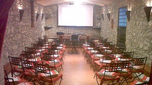 A classroom with stone walls, wooden chairs, and a projector screen at the front. - Villa Life in Vicchio; the Tuskan way (Vicchio)