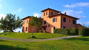 A two-story house with a sloped roof, a large lawn, and a tree in the foreground. - Belvilla by OYO Giaggiolo (Stabbia)