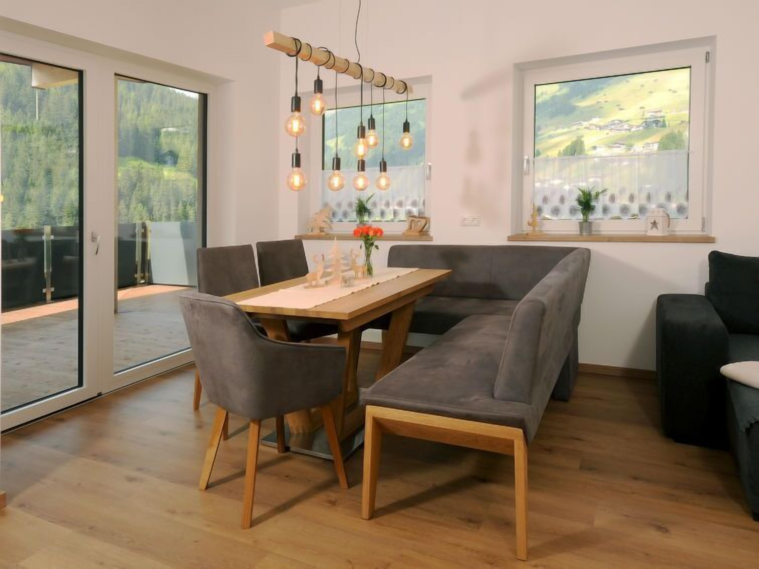 A modern dining area with a wooden table, grey upholstered chairs, and a unique light fixture.