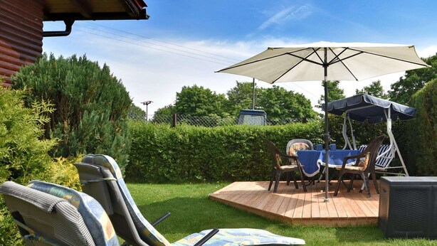 Een terras met twee loungestoelen, een tafel en een parasol.