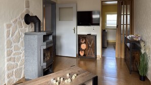 Een woonkamer met een stenen muur, een open haard, een televisietoestel en een houten tafel met dobbelstenen.
