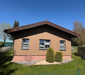 A small, single-story building with a sloped roof, two windows with shutters, and a brick foundation. - Friedlicher Waldurlaub in Altenfeld (Altenfeld)