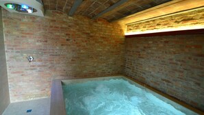 Ein Spa-Raum mit Backsteinwand, einer Badewanne und einer Deckenleuchte.